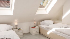 Een slaapkamer met twee bedden, een nachtkastje met een lamp en een dakraam.