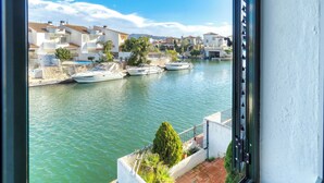 Un port esportiu amb vaixells amarrats, cel serena i edificis d'arquitectura mediterrània.