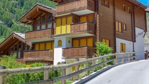 A multi-story wooden chalet with balconies, set against a mountainous backdrop. - La Prairie by Interhome (Zermatt)