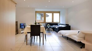 A modern, well-lit room with a dining table, a sofa, and a bed. - La Prairie by Interhome (Zermatt)