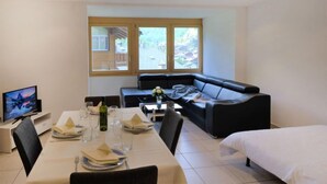A modern hotel room with a dining area, a black leather sofa, a bed, and a TV. - La Prairie by Interhome (Zermatt)