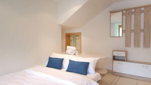 A modern bedroom with a bed, a bedside table, a mirror, and a wardrobe. - La Prairie by Interhome (Zermatt)