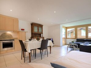 A modern kitchen with a dining area, a sofa, and a large window. - La Prairie by Interhome (Zermatt)