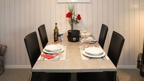 Mesa posta com pratos, copos, uma garrafa e um vaso com flores.