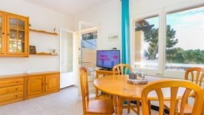 Un comedor acogedor con mobiliario de madera, un televisor y vistas al exterior.