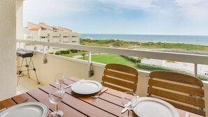 A balcony with a table set for two, overlooking a coastal view with buildings and greenery. - Les Goelettes by Interhome (Saint Cyprien)