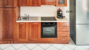 Een keuken met houten kastjes, een roestvrijstalen koelkast, een fornuis en een koffiezetapparaat.