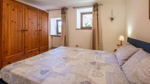 Een slaapkamer met een groot bed, een houten garderobe en een raam met gordijnen.