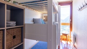 Una habitación pequeña con literas, una mesita y vistas al exterior.
