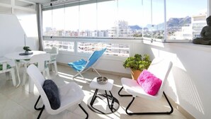A modern balcony with a white chair, a blue lounge chair, a small table, and a potted plant. - Esmeralda 02 by Interhome (Calpe/Calp)