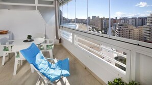 A balcony with a city view, white furniture, and a small table with a plant. - Esmeralda 02 by Interhome (Calpe/Calp)