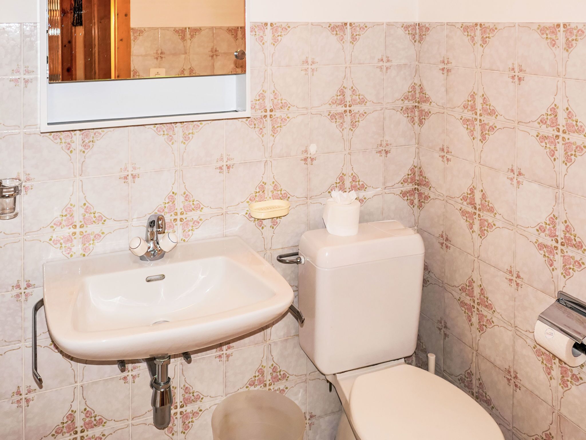 A bathroom with a sink, toilet, and a mirror.