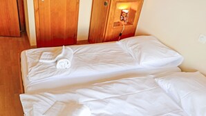 A hotel room with two beds, each with white linens and a rolled towel.