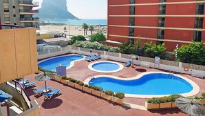 Un hotel con area piscina, comprensiva di diverse piscine e lettini.