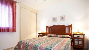 Una camera da letto con un letto di legno, due comodini, una finestra con tende e due quadri appesi al muro.