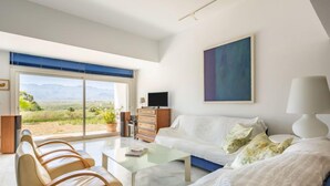Ein modernes Wohnzimmer mit einer Couch, Sesseln, einem Couchtisch und einem Fernseher.