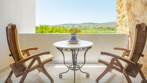 Ein Balkon mit Tisch und zwei Stühlen, mit Blick auf eine grüne Landschaft.