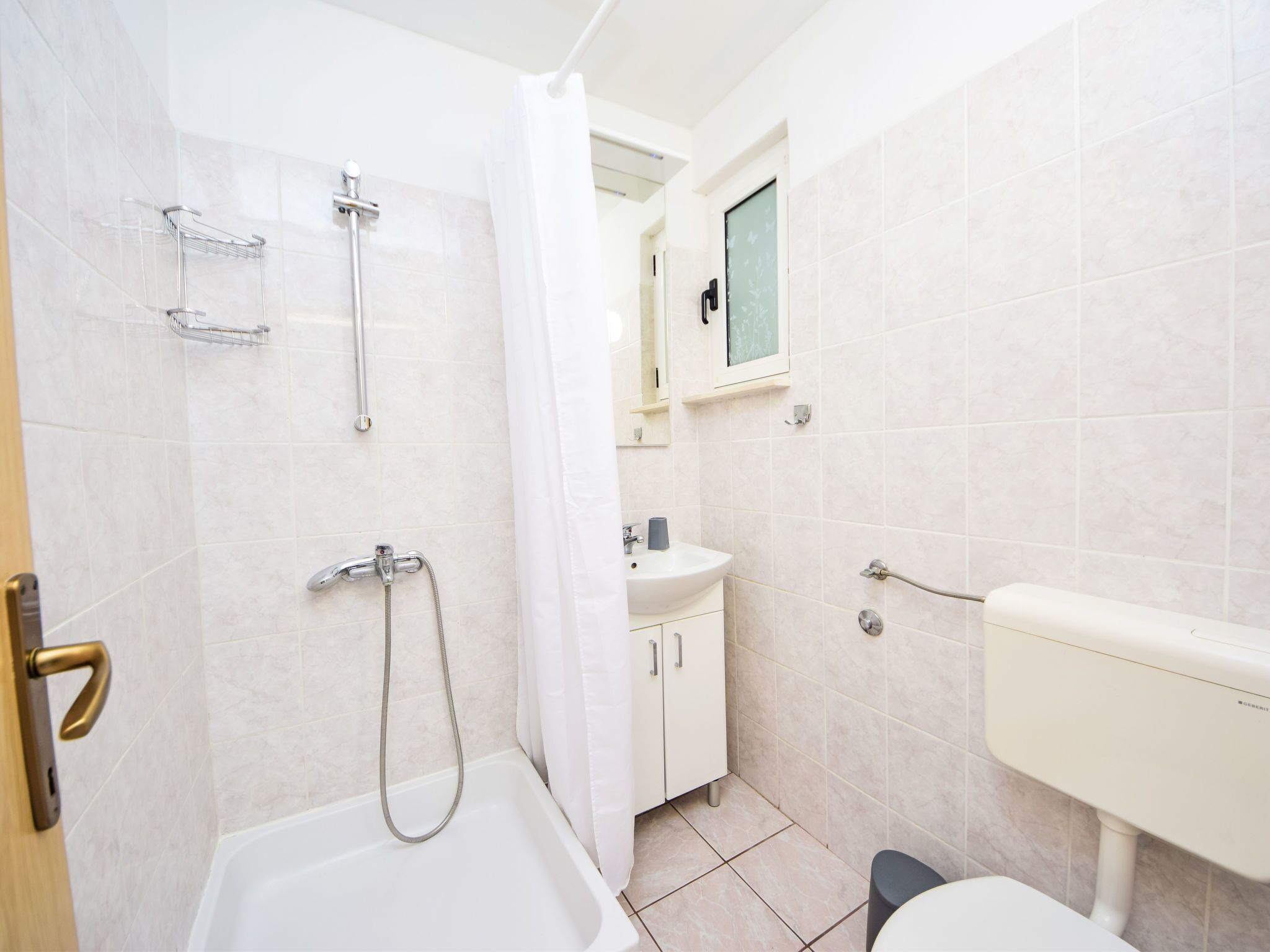 Une salle de bain équipée d’une douche, de toilettes, d’un lavabo et d’un meuble de rangement.