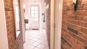 A hallway with brick walls, a white door, and a tiled floor. - Klaffmuschel by Interhome (Norddeich)