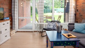 A cozy living room with a blue table, a sofa, and a TV on a brick wall. - Klaffmuschel by Interhome (Norddeich)