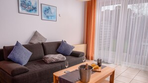 Ein modernes Wohnzimmer mit einem braunen Sofa, gemusterten Kissen, einem Holztisch und einem Weinglas.