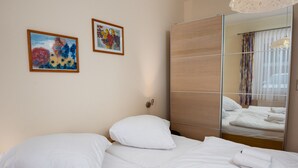 Ein Hotelzimmer mit einem Bett, zwei gerahmten Bildern, einem Spiegel und einer Pendelleuchte.