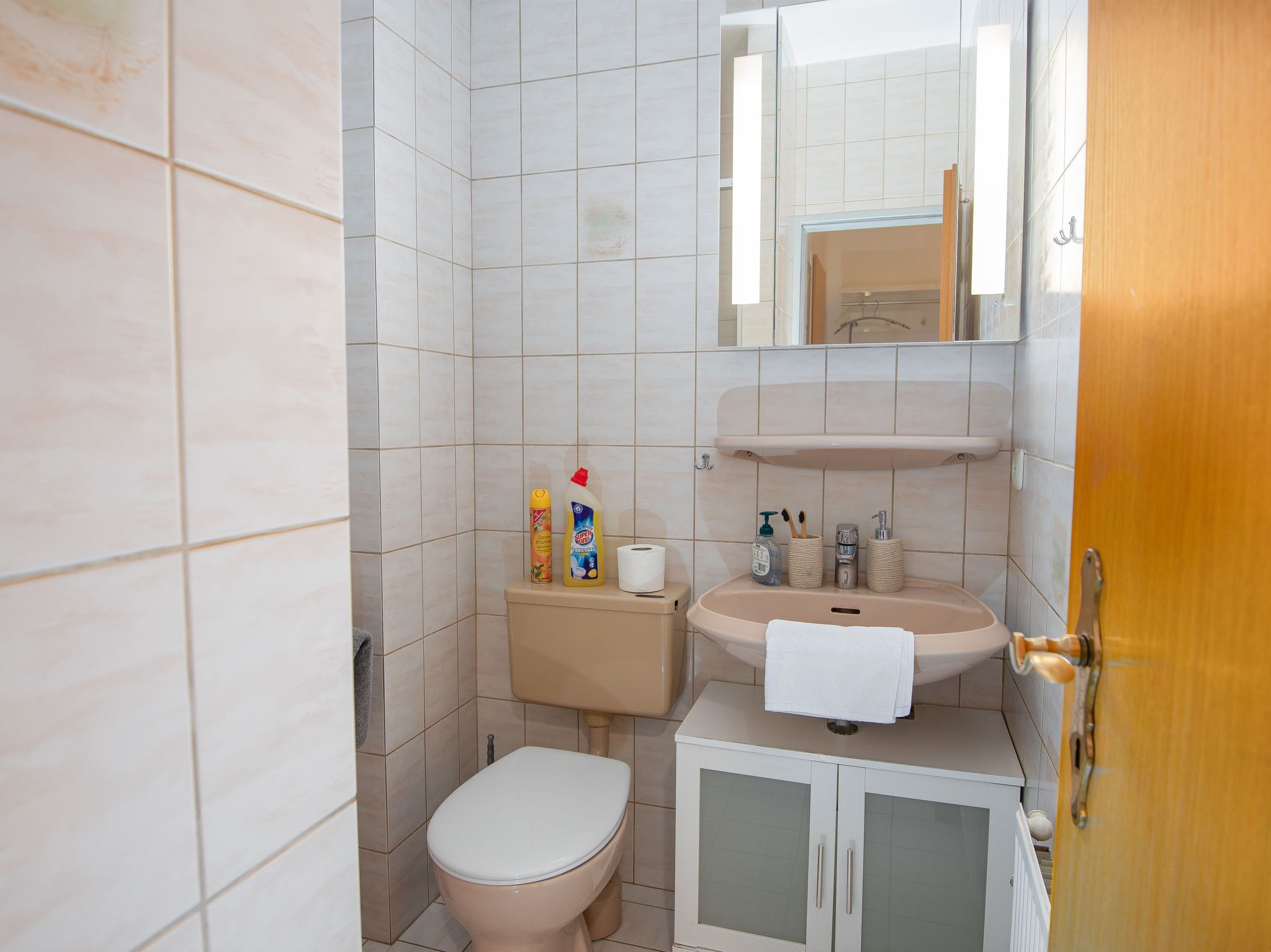 A small bathroom with a toilet, sink, and cabinet.