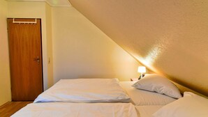 Une chambre avec deux lits, une porte en bois et une table de chevet avec une lampe.