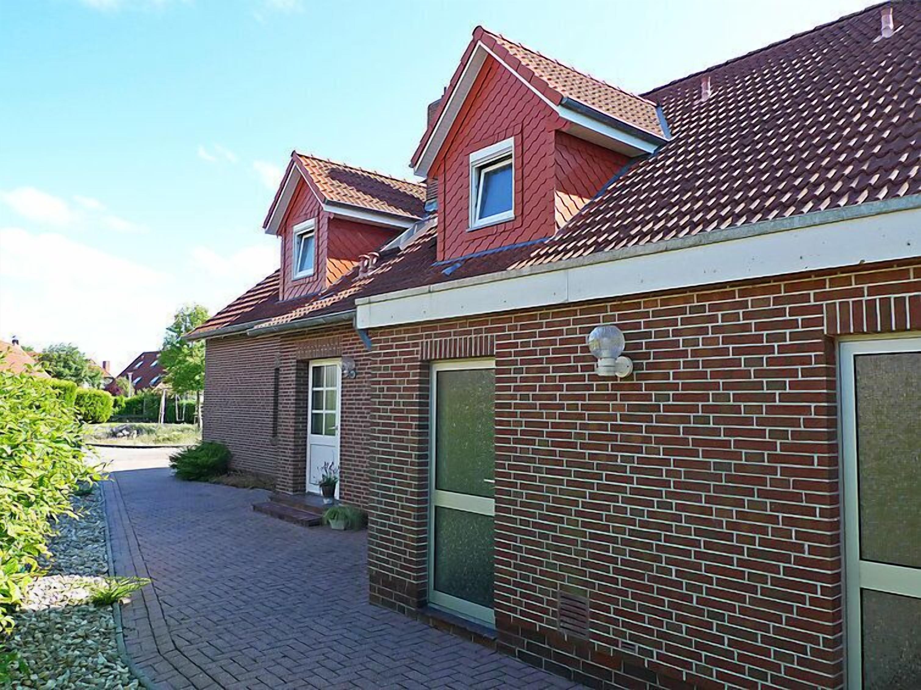 A two-story brick house with a red-tiled roof, a front door, and a small window.