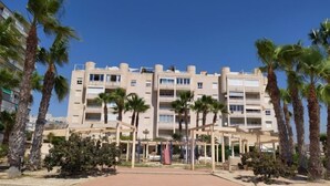 Un hôtel à plusieurs étages doté de balcons, de palmiers et d’une cour intérieure.