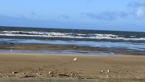 Een strand met golven en een heldere lucht.