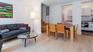 En moderne stue med sofa, sofabord og et spiseområde med stole og bord.