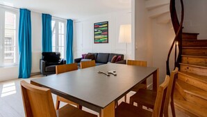 En moderne stue med et træspisebord, stole, en sofa og en trappe.