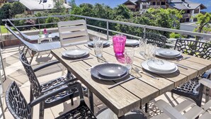 A wooden dining table set outdoors with metal chairs, a pink glass, and plates.