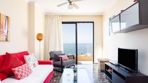 Un soggiorno moderno con divano, televisione e un balcone con vista.