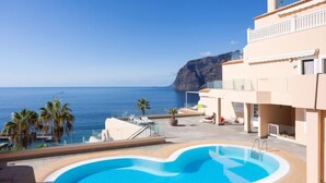 Un'area piscina con vista sul mare e un edificio con un balcone.