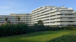A modern multi-story hotel with a flat roof and balconies, surrounded by well-maintained lawns and shrubs. - Le Beaupré by Interhome (Canet-Plage)