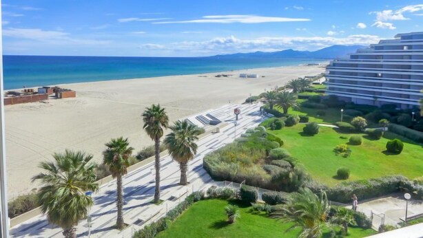 A beachfront hotel with a sandy beach, palm trees, and a clear blue sky. - Le Beaupré by Interhome (Canet-Plage)