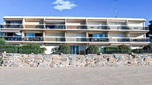 A multi-story building with balconies, a stone wall in front, and a clear blue sky. - De la Plage by Interhome (Cavalaire)