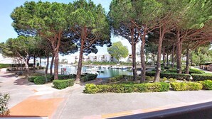 A view of a park with trees, a body of water, and buildings in the background. - Port d'Attache by Interhome (Saint Cyprien)