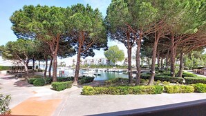 A landscaped area with trees, a water body, and buildings in the background. - Port d'Attache by Interhome (Saint Cyprien)