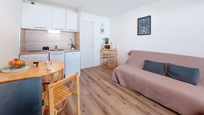 A compact living space with a kitchenette, a dining area, a sofa, and a small table. - Port d'Attache by Interhome (Saint Cyprien)