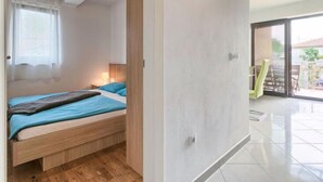 Ein Schlafzimmer mit einem Bett, einem Fenster mit Jalousien und Blick nach draußen.