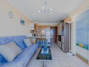 A compact living space with a kitchenette, a sofa, a coffee table, and a view of the outdoors.