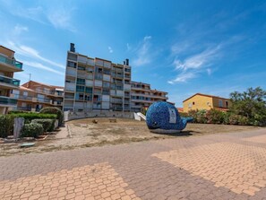Un edificio residencial con varios balcones, un patio empedrado y una gran escultura de ballena azul.