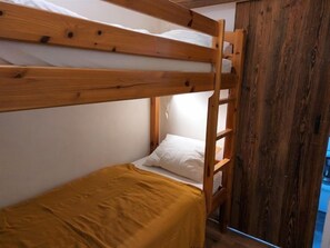 Ein Etagenbett mit Holzgestell und einer gelben Bettdecke.