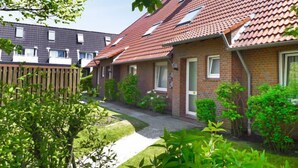A row of brick houses with red-tiled roofs, a wooden fence, and green plants. - Muschelweg by Interhome (Norddeich)