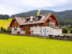 A two-story chalet with a sloped roof, wooden exterior, and a fenced property.