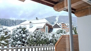 Ein Holzbalkon mit Blick auf schneebedeckte Gebäude und einen Berg im Hintergrund.