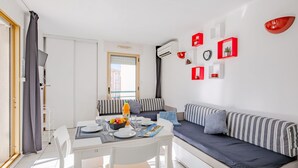 Uma sala de estar moderna com área de jantar, apresentando um sofá, uma mesa de jantar com cadeiras e uma janela com cortinas.